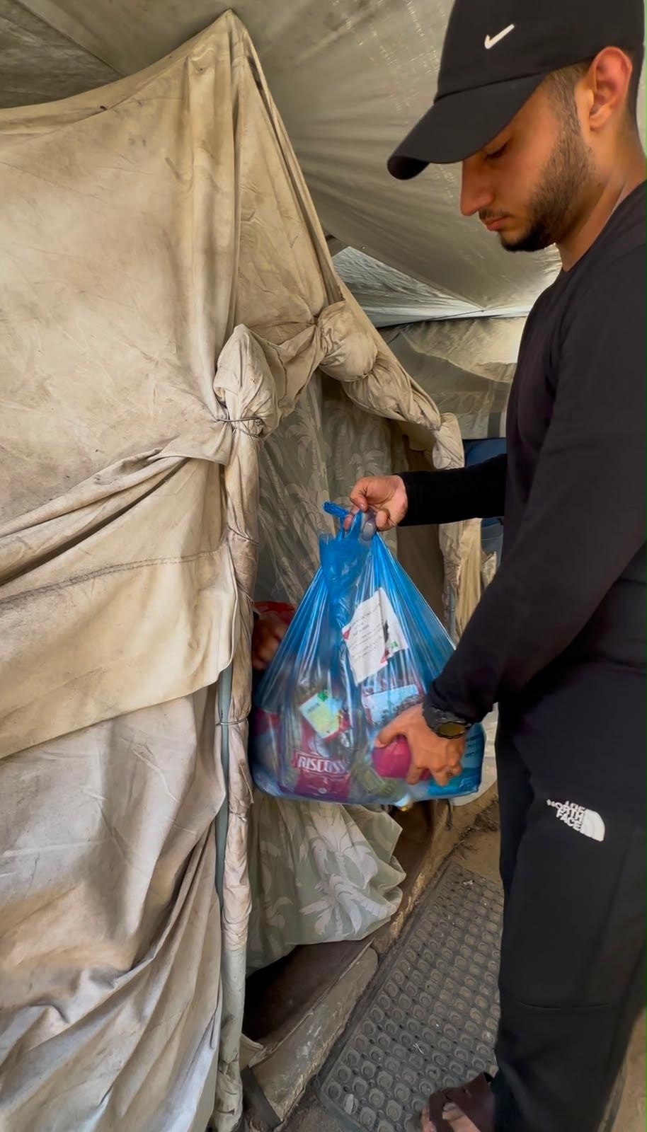 Volunteer with food bag inside tent